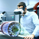 A man in a factory wears a headset as he looks at a virtual version of machinery.